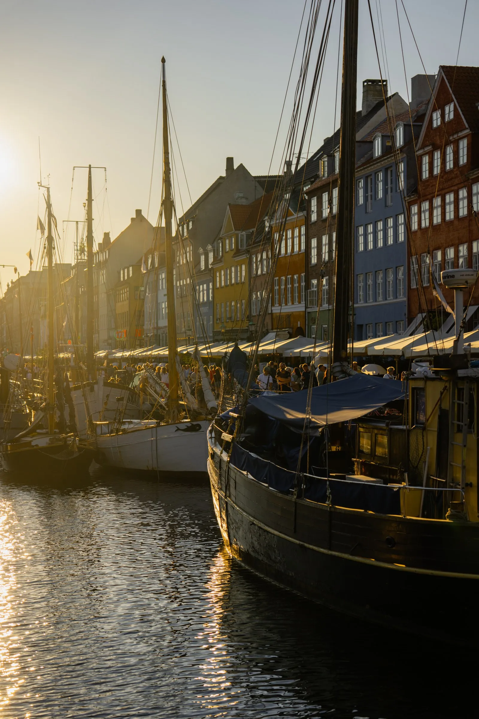 Golden evening light falls across moored boats and waterside buildings