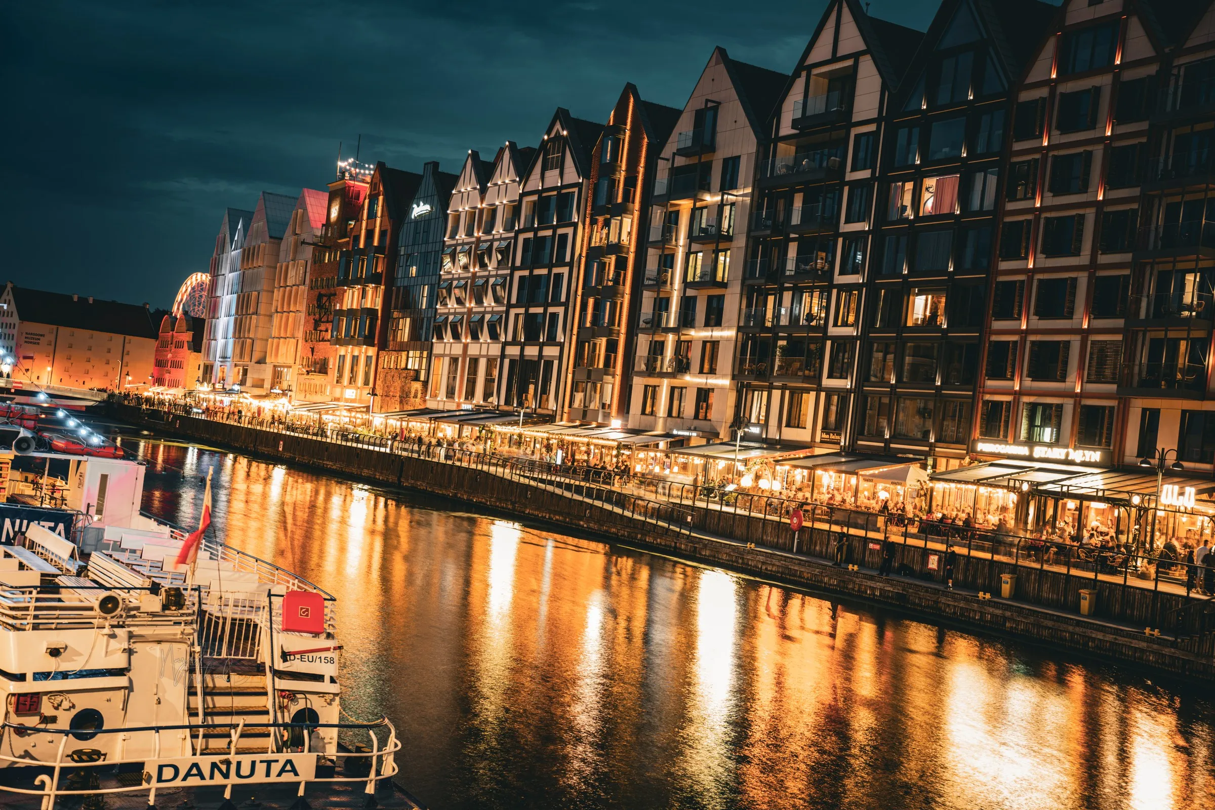 Old-town facades and boats glow beside a canal at night